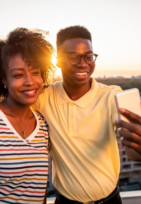 Two young friends making a self portrait at the rooftop. It has beautiful view on the city during sunset